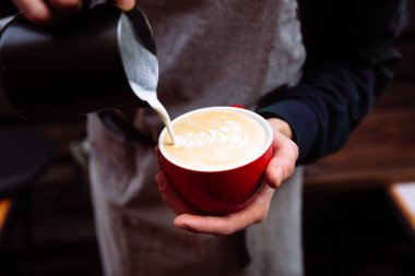 Barista bir fincan kahveye taze süt koyar. Çiçek Latte sanatı