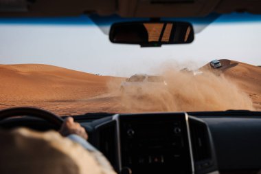 Dubai, Birleşik Arap Emirlikleri - 01 Temmuz 2021: Kum çölünde yarış. Yarış yarışı çölü. Araba toz bulutlarıyla yoldan çıkıyor. Yabanda engellerle yarışan off road aracı