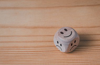 Güler yüzlü ve hüzünlü semboller ahşap arka plandaki tahta bloklarda.