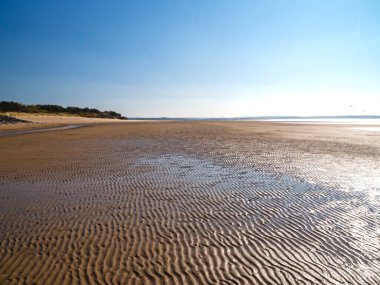 Galler 'in Burry Limanı' ndaki kumlu sahile bak. Dalgaların çekildiği yerde tırmık izleri var.