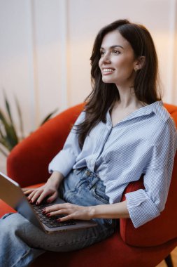 Dizüstü bilgisayarda çalışan ve gülümseyen serbest çalışan kadın..