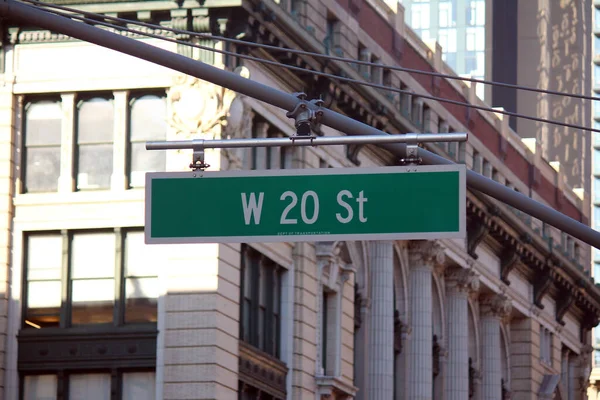 緑の大きな西20丁目標識がマンハッタンの中心街のアーチポールにかかっている — ストック写真