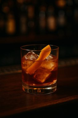 Klasik Negroni kokteyli. Buzlu, portakal rengi bir karışım. Sıcak mum ışığında parıldıyor..
