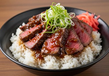 Lezzetli Japon sığır eti kasesi (Gyu-don) mükemmel kurutulmuş biftek dilimleri, yeşil soğan ve kırmızı zencefil ile kaplı, kabarık beyaz pirinç üzerinde servis edilir siyah kase içinde.