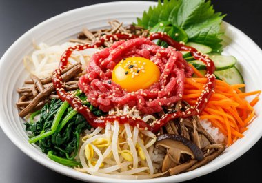 Kore mutfağı, özenle sunulmuş bir kase Yukhoe Bibimbap, taze malzemelerini sergiliyor ve renkleri davet ediyor..