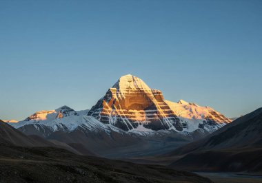 Haşmetli ve kutsal Kailash Dağı, Himalayalar 'ın engebeli bir arazisinin üzerinde yükseliyor, aşağıdaki vadide bir nehir kıvrılıyor..