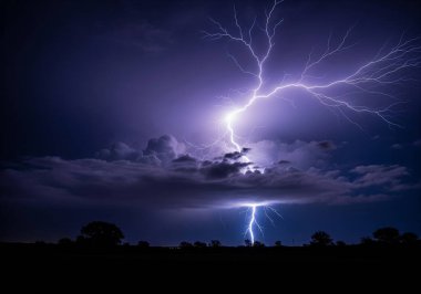Çarpıcı bir yıldırım fırtınalı gece gökyüzünü aydınlatır karanlık, siluetli bir manzara üzerine..