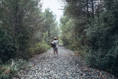 Gezgin adam terk edilmiş tren raylarında yürüyor.