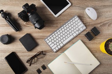 Fotoğrafçı çalışma yerinin üst görüntüsü, dijital kameralı çalışma alanı konsepti, laptop, hafıza kartı, akıllı telefon ve harici sabit disk.