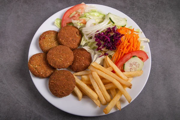 Salatalı falafel tabağı ve kırsal alanda izole edilmiş patates kızartması.