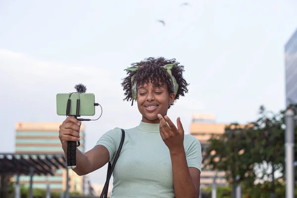 Portrait of a young African American woman streaming live on her smartphone while walking through the city. young blogger concept, copy space.