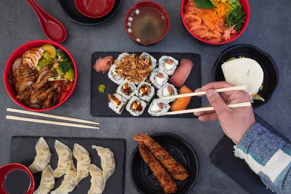 寿司ロールを食べる 和食レストラン 各種寿司プレート 素朴な背景を持つ圧延箸で手を閉じる ストックフォト
