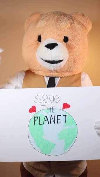 一个头戴泰迪熊黄色背景的男人拿着一个标牌 上面写着 拯救地球 社交网络的垂直视频 — 图库视频影像
