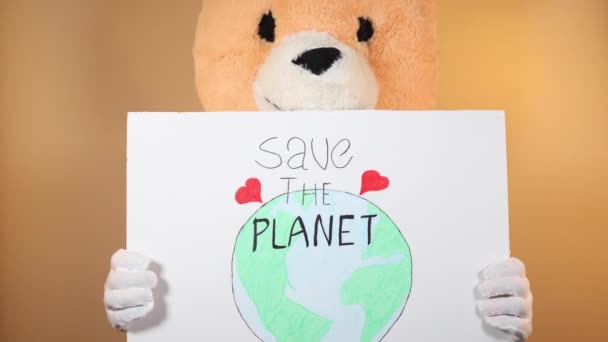 一个头戴泰迪熊的男人指着一个标牌 上面写着 拯救地球 用黄色背景隔开 — 图库视频影像