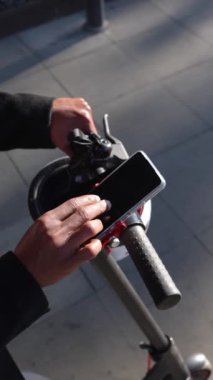 Close up of hands with phone. Businessman taking e-scooter or bike. Phone app for scooter rental. Ecological city transport.