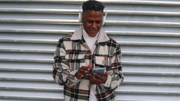 Retrato Hombre Moreno Con Auriculares Usando Teléfono Inteligente Para Escuchar — Vídeo de stock