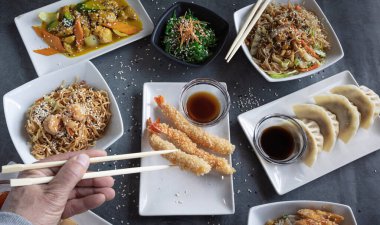 Bir Japon restoranında yemek çubuklarıyla yemek yiyen bir adamın ellerine bakın..