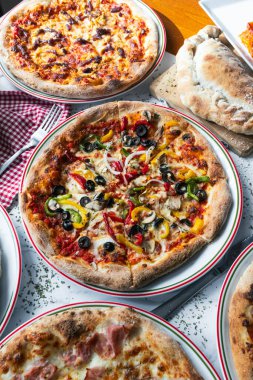 Menüyü tatmak ya da hazırlamak için çeşitli pizzalar masanın üzerinde.