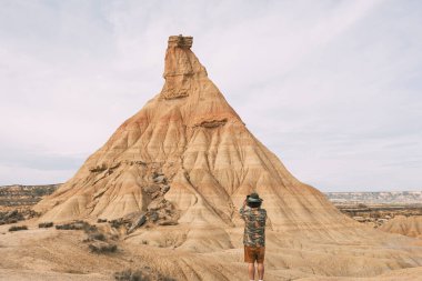 Rear View Of A Man With A Hat Taking A Photo With A Smart Phone In The Bardenas Desert. Navarre