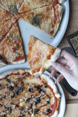 Ellerinde peynirli dört dilim pizza.