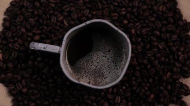 Masanın üzerinde sıcak espresso kahvesi ve kavrulmuş fasulye arkaplanı. Kahve çekirdeğinin üzerinde bir fincan sade kahve duruyor..