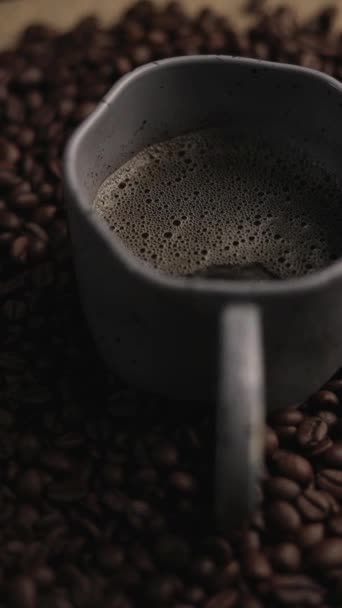 Zamknij Filiżankę Kawy Tłem Obrotowych Ziaren Kawy Pionowe Wideo — Wideo stockowe
