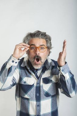 Şaşırmış bir adamın portresi gözlüklerine dokunuyor ve beyaz arka plandaki kameraya bakıyor.