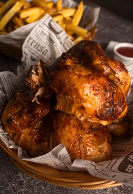 Lezzetli kızarmış tavuk ve kızarmış patates kızartması bir sepetin içinde gazete astarı ve yanında sos ile servis ediliyor.