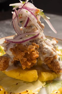 Ekmekli balık, kremalı tartar sosu, patates püresi, taze marul ve canlı kırmızı soğan salatası içeren bir gurme tabağının yakın çekimi.