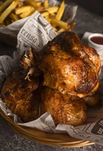 Lezzetli kızarmış tavuk ve kızarmış patates kızartması bir sepetin içinde gazete astarı ve yanında sos ile servis ediliyor.