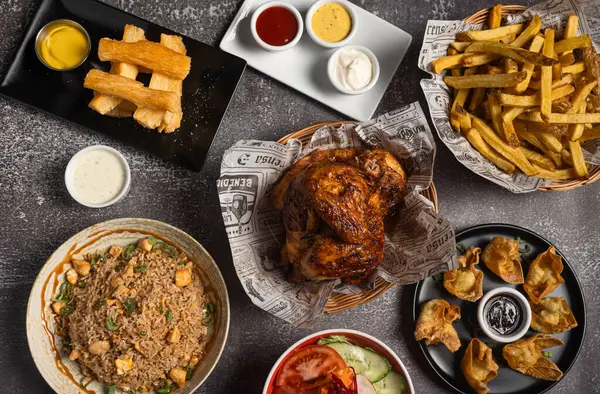 Kızarmış tavuk, patates kızartması, kızarmış yuca, kızarmış pilav, salata, mantı ve soslar da dahil olmak üzere bir dizi lezzetli yemeğin yer aldığı genel bir manzara.