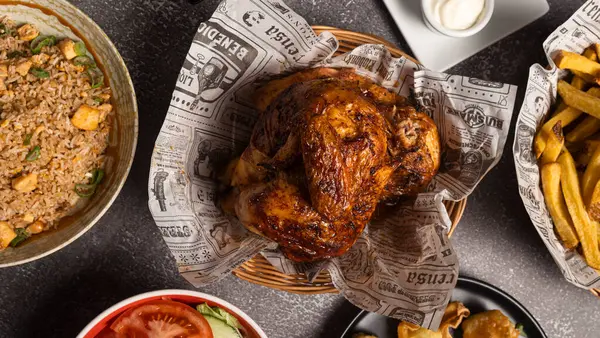 Çeşitli mezelerle servis edilen kızarmış tavuğun genel görünüşü, baştan çıkarıcı ve baştan çıkarıcı bir yemek yaratıyor.