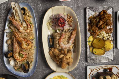 Deniz ürünleri, pirinç, ceviche ve patatesli et de dahil olmak üzere çeşitli Peru yemeklerini gösteren bir masanın genel görünümü