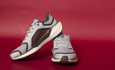 Şık koşu ayakkabıları canlı kırmızı bir arka planda sergileniyor, tasarımları ve özellikleri sergileniyor.