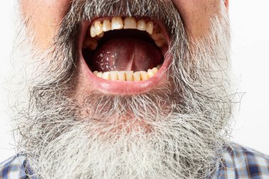 Uzun beyaz sakallı, sarı dişli ve dilli yaşlı bir adamın yakın çekimi.