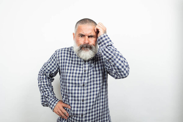 Страстный зрелый мужчина с бородой и усами, трогающий голову, испытывающий сильную головную боль или пытающийся вспомнить что-то важное