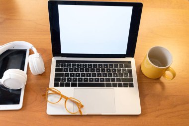 Konforlu çalışma alanı dizüstü bilgisayar, kulaklık ve kahve kupası içeriyor.