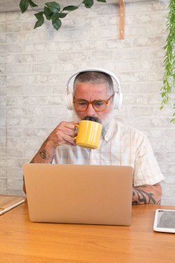 Olgun bir serbest yazar evinden uzakta çalışırken kahve içiyor ve verimli bir günün tadını çıkarıyor.