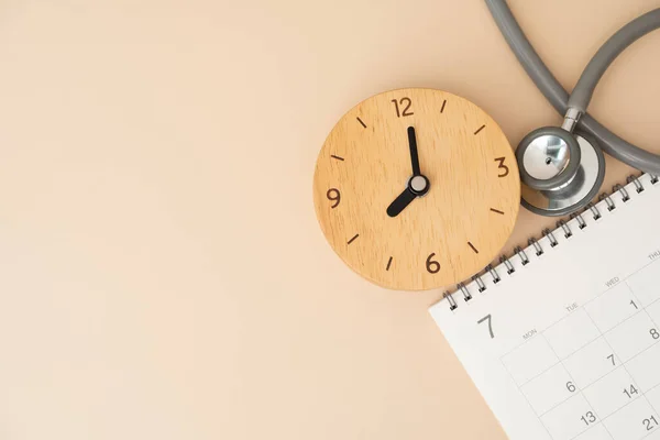 stock image Top view of stethoscope, alarm clock and calendar on the brown background, schedule to check up healthy concept