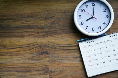 Takvimi ve saati ahşap masa arka planında kapat, iş toplantısı ya da seyahat planlama konsepti için planlama