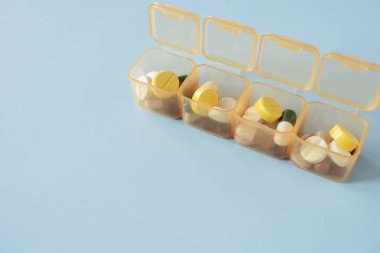 Mavi masadaki ilaç kutusuna koyulmuş renkli ilaç veya hap, sağlıklı ve ilaç konsepti