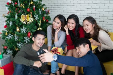 Asyalı arkadaş grubu ev partisinde akıllı telefonlu selfie çekiyor. Şirket, kutlama ve tatil konsepti.