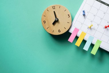 close up of clock and calendar on the green table background, planning for business meeting or travel planning concept