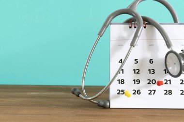 close up of stethoscope and calendar with green background, schedule to check up medical healthy concept