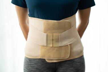 young woman wearing back support for protect her back, medicine and healthy concept