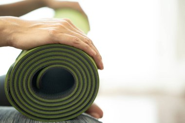 Spor ve sağlıklı bir konsept için egzersiz sınıfında yoga minderi tutan genç bir kadın.