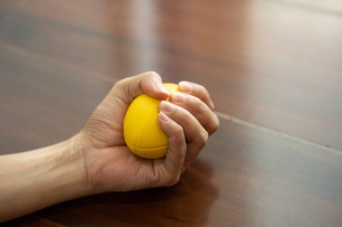 Hands of a woman squeezing a blue stress ball for work out or relax at home