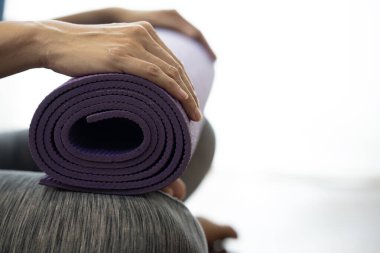 Spor ve sağlıklı bir konsept için egzersiz sınıfında yoga minderi tutan genç bir kadın.