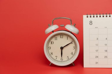 Kırmızı masa arkaplanındaki takvim ve alarmın kapatılması, iş toplantısı ya da seyahat planlama konsepti