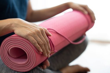 Spor ve sağlıklı bir konsept için egzersiz sınıfında yoga minderi tutan genç bir kadın.